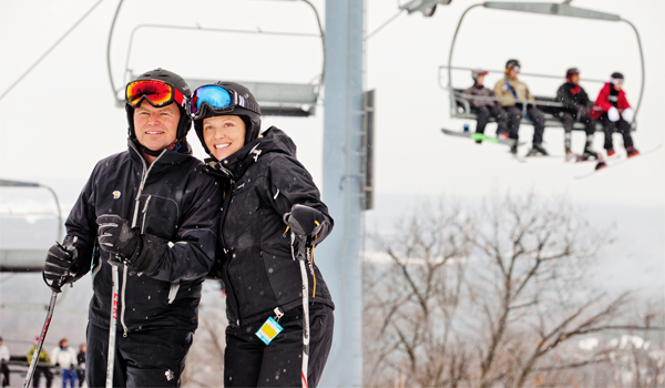 man and woman skiing with chairlift in background