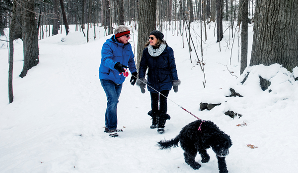 man and women walking dog on winter trail