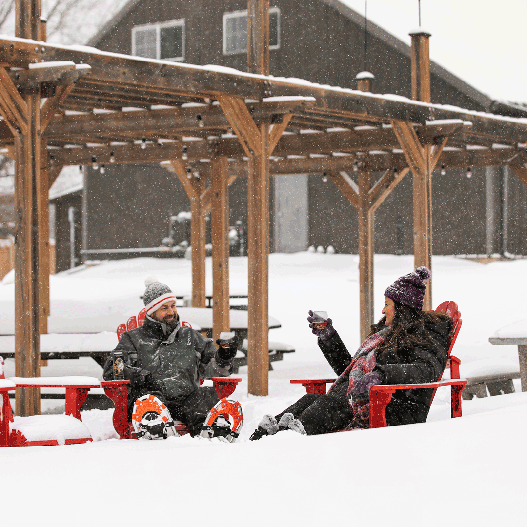 Man and woman enjoying Heritage Estate wine in snowy outdoors after snowshoeing
