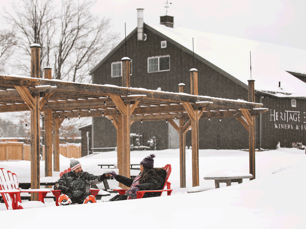Man and Women sitting in chairs in front of Heritage Estates in snow