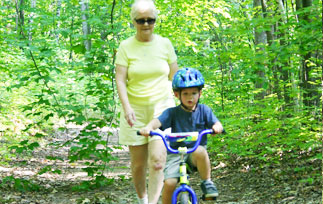 A kid and his grandmother cycling in the forest