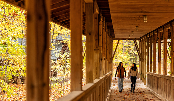 Friends walking along covered bridge at the Tiffin Centre during fall