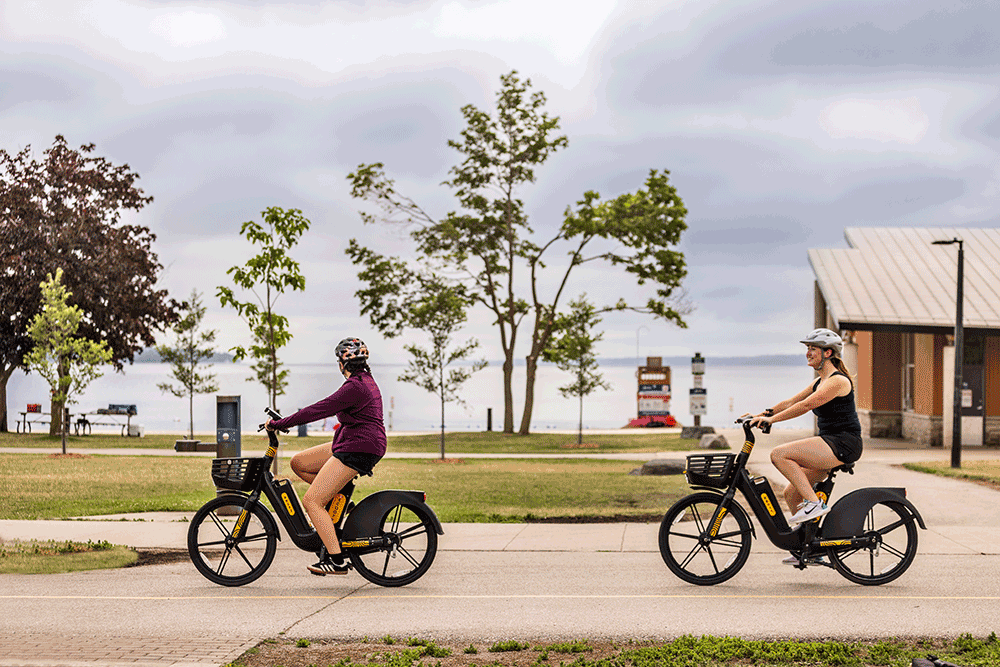 Scooty two people cycling along waterfront path