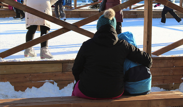 Mother and child sitting on bench near skating rink