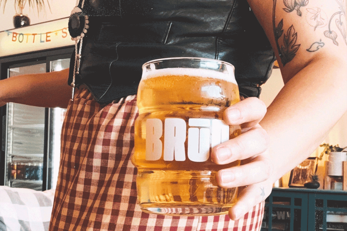 Person holding glass full of beer at Brud Bar and Bottle Shop