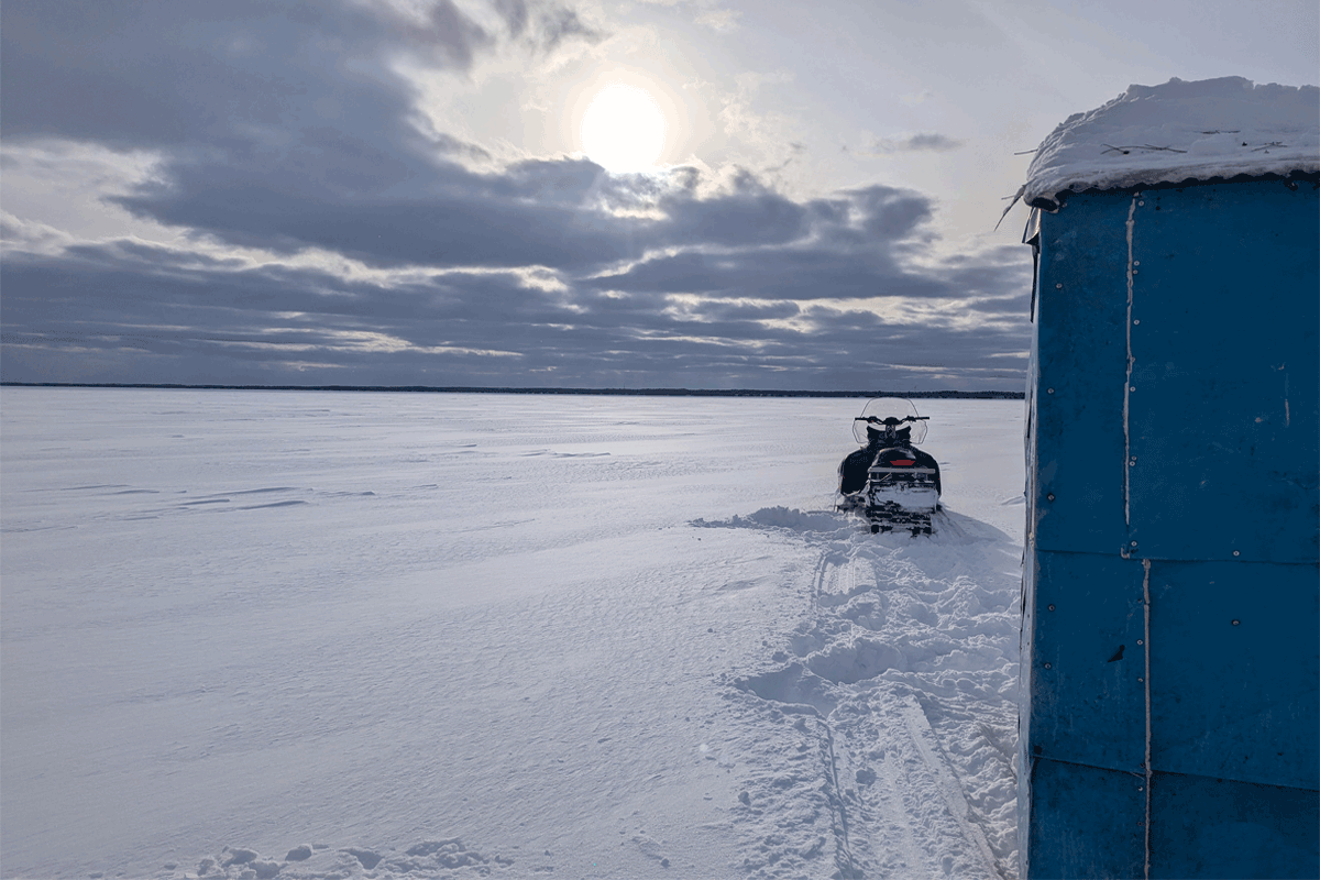 Snowmobile and ice hut on snow covered frozen bay