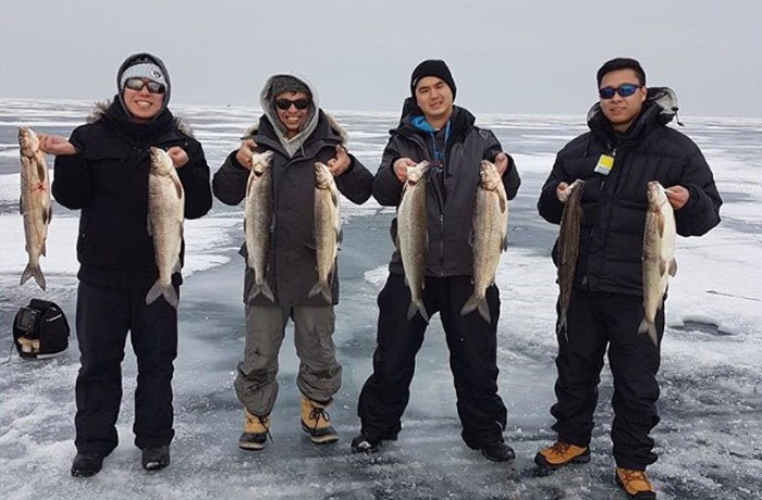 Group of friends showing off their ice fishing catch with Fish Crazy Guide Service