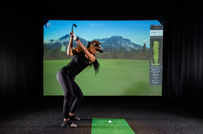 Woman taking a swing at virtual golf in North Swing Golf Lounge in Barrie