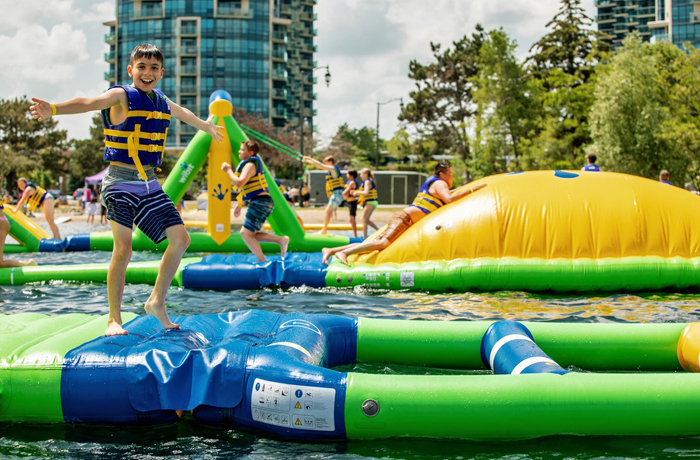 Kid playing on splash on water park inflatable obstacle course